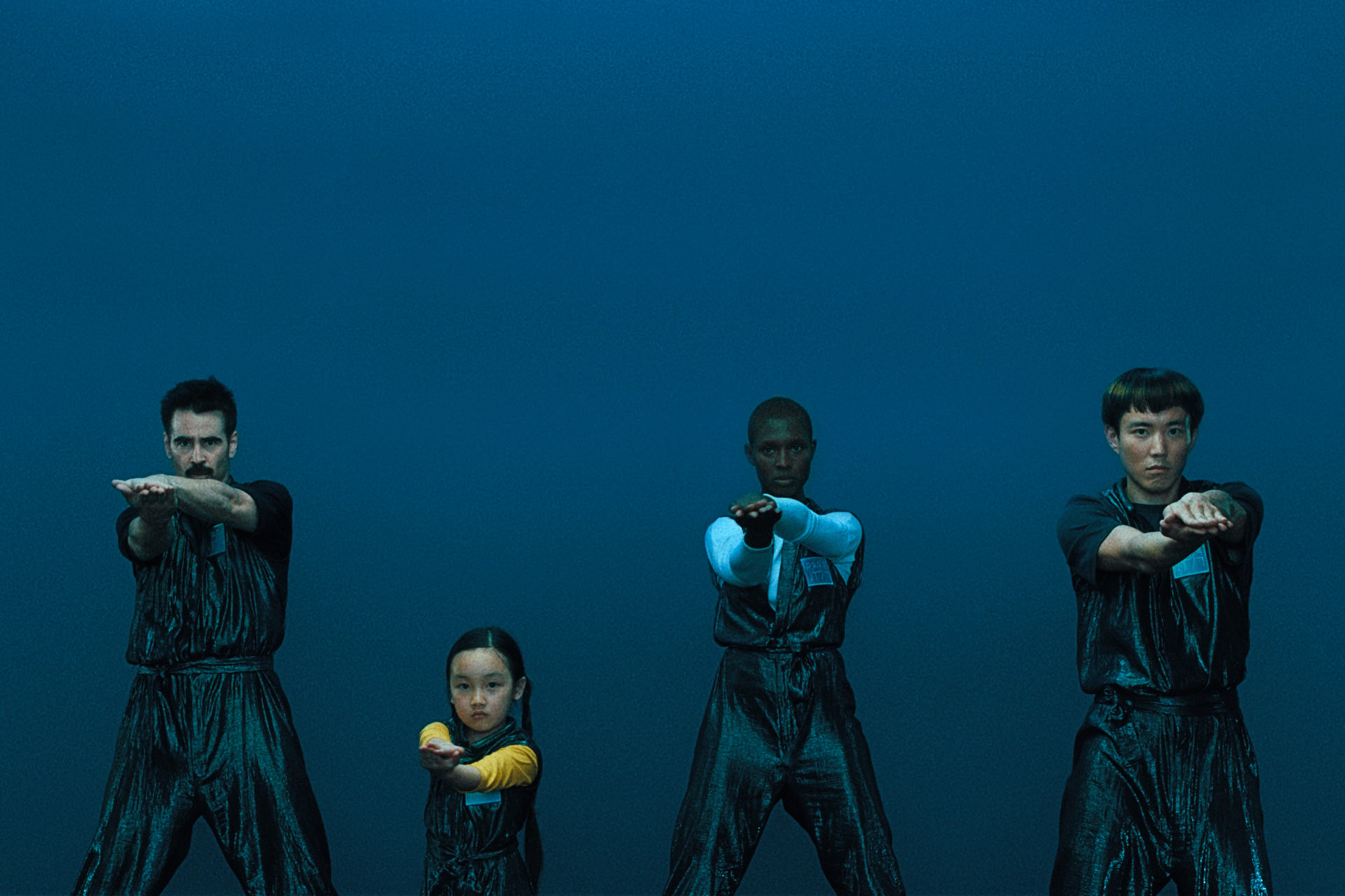 Une famille exécute une chorégraphie de danse, sur un fond monochrome bleu.